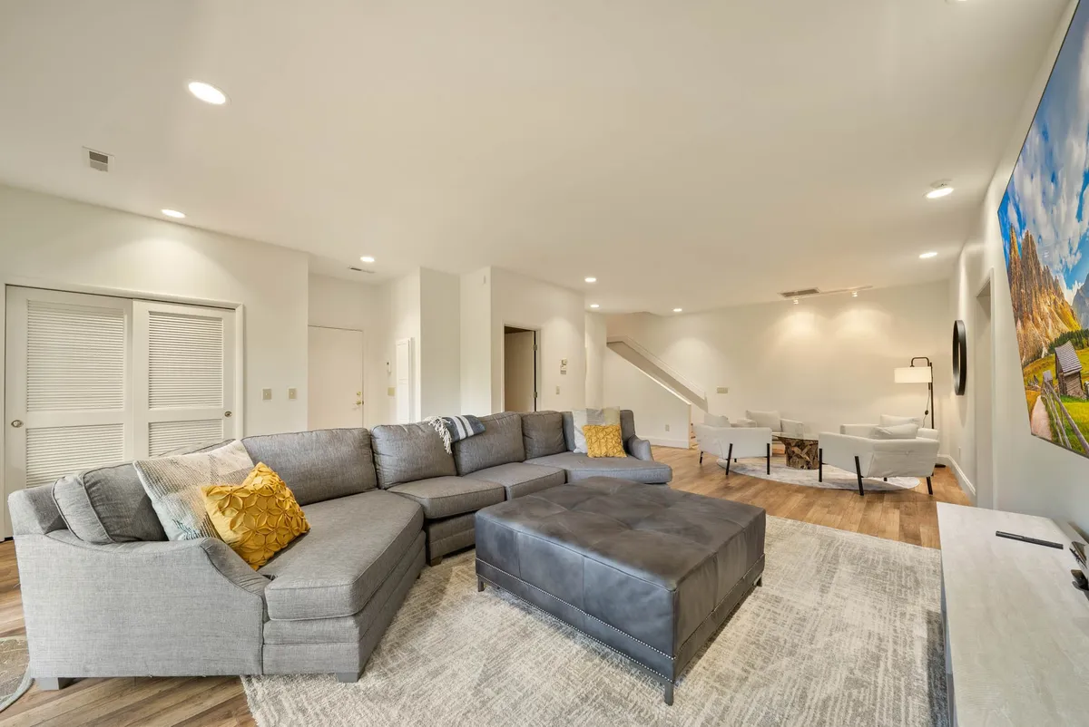 A sectional sofa and coffee table create an intimate entertainment nook, with a TV mounted on the wall. The arrangement invites both casual hangouts and group activities, reinforcing the idea of a dedicated space for togetherness and downtime.