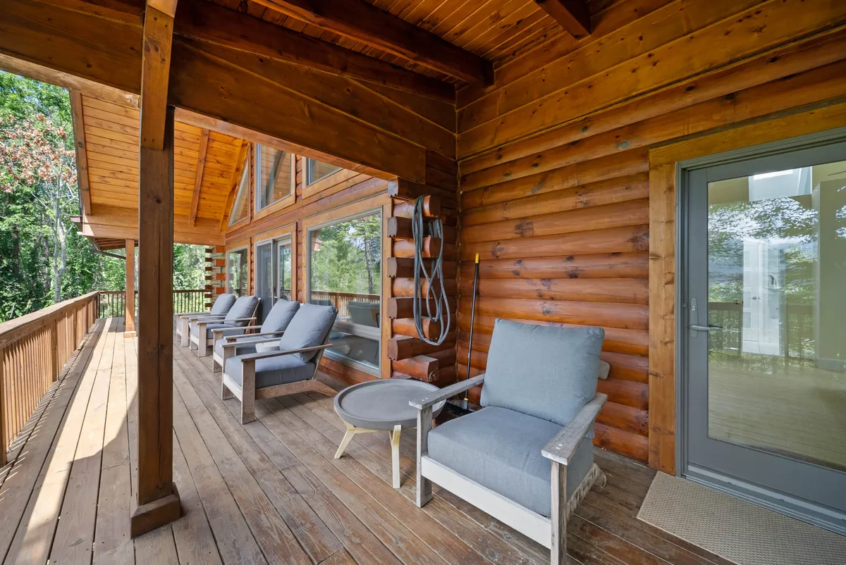 This photo features a wooden deck with comfortable seating and large windows, surrounded by natural scenery. The setup suggests spaces for enjoying a book, sipping coffee, or hosting gatherings, with tranquil views all around.