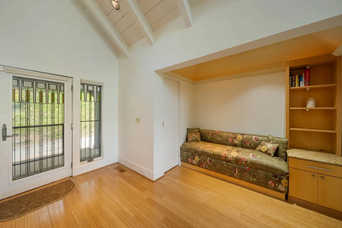 The image shows a welcoming entryway with a front door featuring decorative glass, a cozy bench seating area, and built-in shelving. Natural light streams in, creating an inviting first impression and hinting at the warmth and comfort inside.